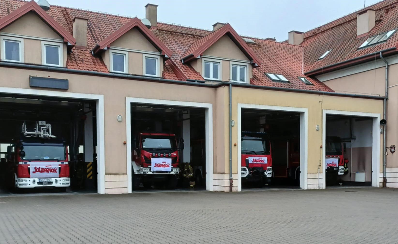 Akcja protestacyjna Straży Pożarnej. Flagi na budynkach i pojazdach